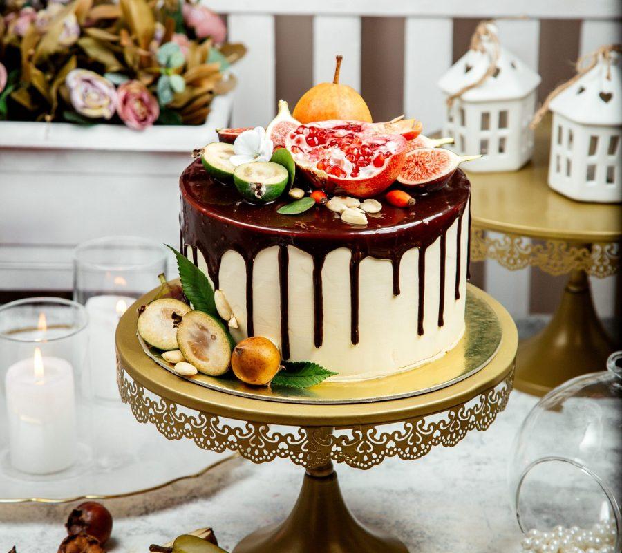 creamy cake topped with chocolate and multiple fruits Drip Cake topped with chocolate and fruits