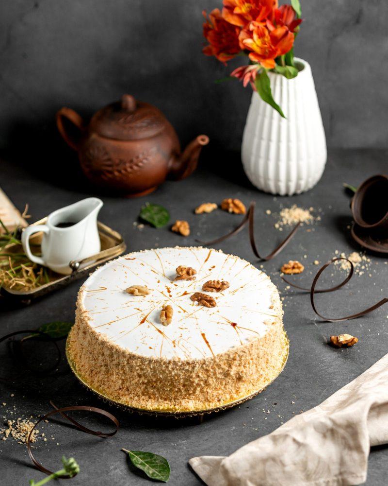 white glazed cake decorated with cake crumbles and walnuts